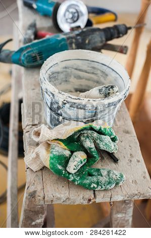 Working Gloves. Do Makeovers. Putty Knife Lying On The Bucket. Tools For Construction And Repair. Se
