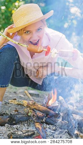 Woman In Straw Hat Try To Bite Sausage On Stick. Girl Eats Sausage On Stick. She Has Strong Appetite