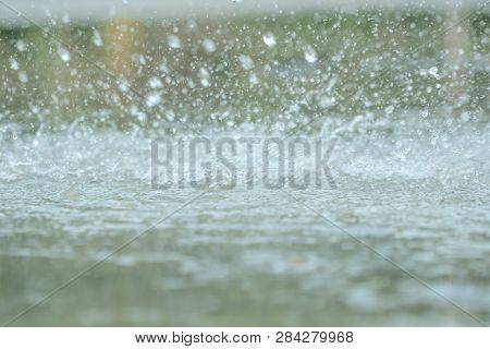 Rain Drops Falling In A Big Puddle On Urban Asphalt In The Town. Raindrops Close-up, Bad Weather In