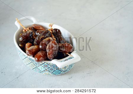 Bowl With Juicy Dates On A Branch On A Gray-blue Background. Healthy Tasty Food. Raw Organic Medjool