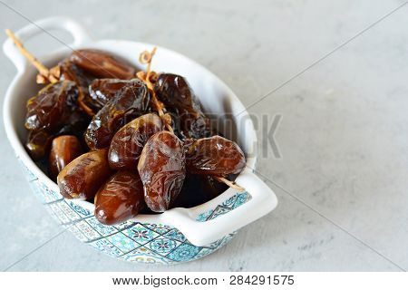Bowl With Juicy Dates On A Branch On A Gray-blue Background. Healthy Tasty Food. Raw Organic Medjool