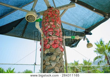 Shower On The Street Of Red Stone Under A Blue Umbrella Near The Beach