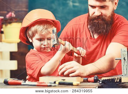 Little Assistant Concept. Boy, Child Busy In Protective Helmet Learning To Use Hammer With Dad. Fath