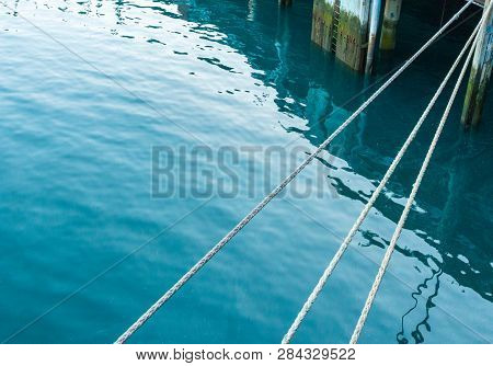 Taut Mooring Lines Attached To Pier At Stern Of Ship.