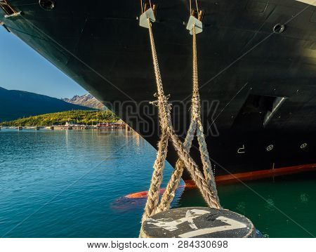 Mooring Lines And Rat Guards Tied At Bow Of Cruise Ship And Dock Bollard In Alaskan Deepwater Termin