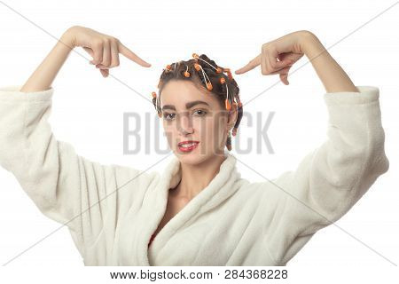 Young Woman In Bathrobe Show At Hair Curlers On Head, Isolated On White Background