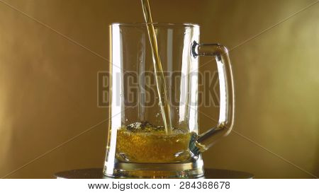 In A Large Mug That Turns Into A Poured Dark Beer On A Golden Background, Oktoberfest