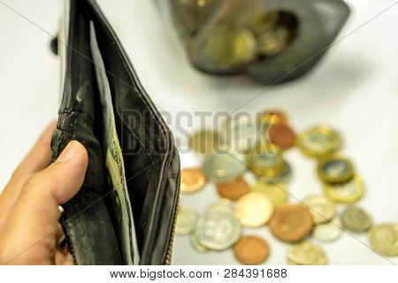 Hand Holding Black Wallet With Only One Bank Note Inside And Blurry Coins Open From The Piggy Bank L