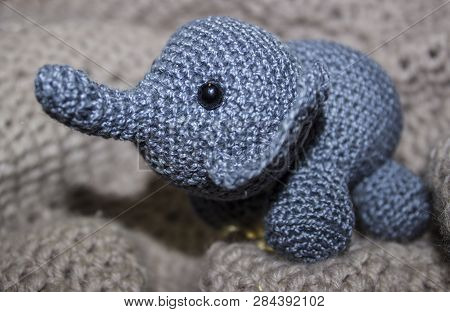 Little Grey Elephant Crocheted Sitting On Knitted Texture With Patterns