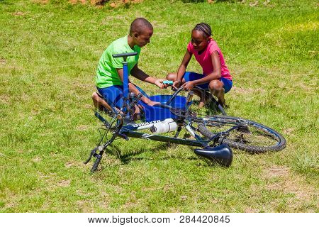 African Children Fixing A Puncture On A Bike