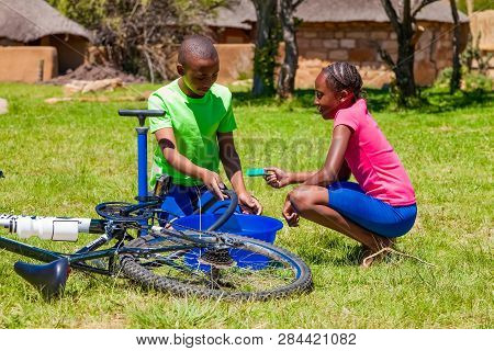 African Children Fixing A Puncture On A Bike