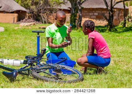 African Children Fixing A Puncture On A Bike