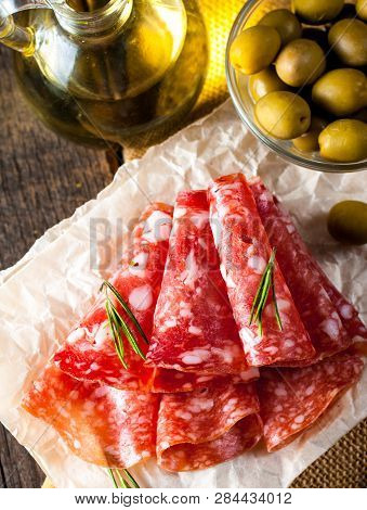 Italian Salami With Olives And Spices On Wooden Background