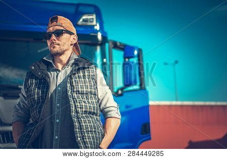 Truck Driving Business Concept. Caucasian Trucker In Front Of His Blue Modern Semi.