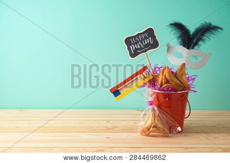Jewish Holiday Purim Background With Bucket, Carnival Mask, Noisemaker And Hamantaschen Cookies On W