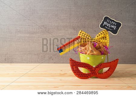 Jewish Holiday Purim Background With Bucket, Carnival Mask, Noisemaker And Hamantaschen Cookies On W