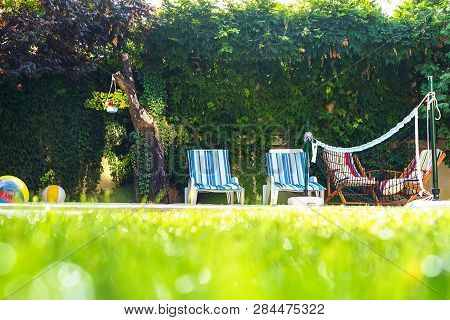 Selective Focus On Green Grass With Water Drops As Dew And Bokeh Background On The House Yard With S