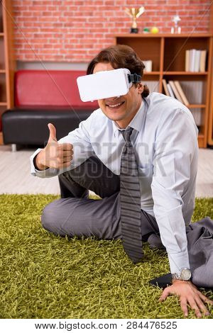 Young employee with virtual glasses during break in the office