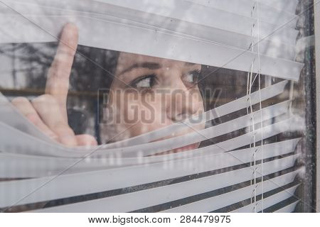 Woman Looking Through The Blinds. Girl Looking Out The Window