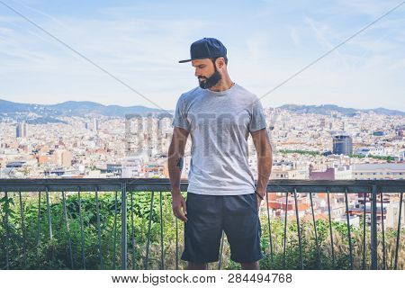 Hipster Handsome Male Model With Beard Wearing Gray Blank T-shirt And A Black Snapback Cap With Spac