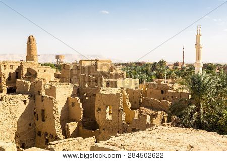 Oasis With Ruins Of Ancient Middle Eastern Arab Town Built Of Mud Bricks, Old Mosque With Minaret. N