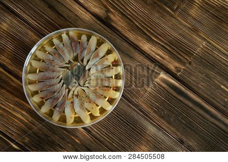 Sliced Scandinavian Herring Fillet With Spices In A Plastic Jar. Table Setting On A Wooden Rustic Ta