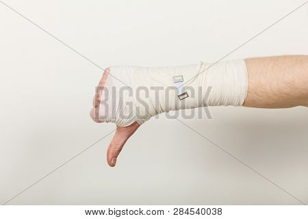Bad News And Information. Medicine Aspects. Male Hand With Bandage Showing Thumb Down Sign Symbol.