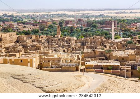 Oasis With Ruins Of Ancient Middle Eastern Arab Town Built Of Mud Bricks, Old Mosque With Minaret. N