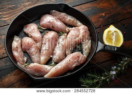 Raw Chicken Breast Mini Fillets In Rastic Cast Iron Skillet, Frying Pan With Herbs And Sea Salt