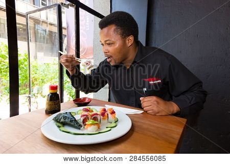 African Man Eating Sushi In A Restaurant
