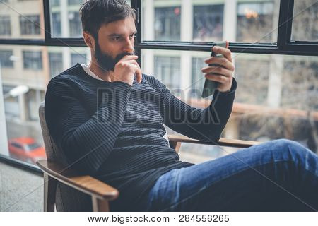 Bearded Hispanic Man In Black Pullover Using Mobile Phone Application For Mobile Blogging.confident 
