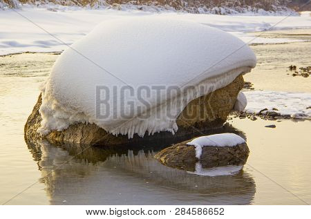 Winter A Huge Stone Lies In A River Covered With Snow Reflected In The Water