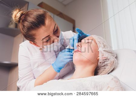 The Doctor Cosmetologist Makes Lip Augmentation Procedure Of A Beautiful Woman In A Beauty Salon.cos