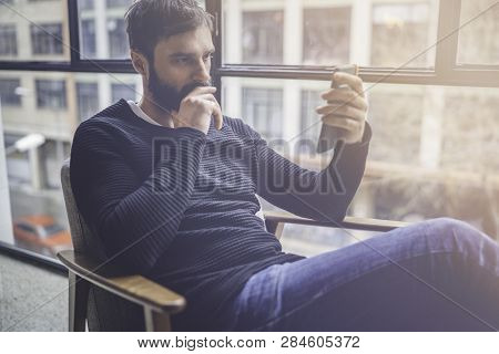 Bearded Hispanic Man In Black Pullover Using Mobile Phone Application For Mobile Blogging.confident 