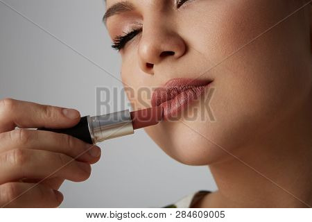 Beatiful Girl With Closed Big Eyes, Thick Eyebrows Doing Make Up With Red Lipstick.model With Light 