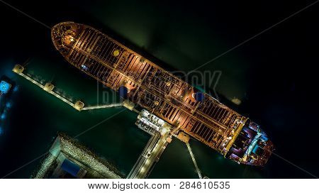 Tanker Ship At The Port, Oil Terminal Tanker Ship Loading At Night, Aerial View.