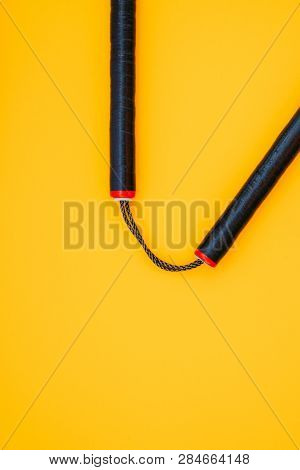 Training Black Nunchaku Is Isolated On A Yellow Background.