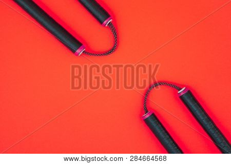 Training Nunchaku Isolated On A Red Background. Asian Nunchaku Weapon On A Red Background And A Plac