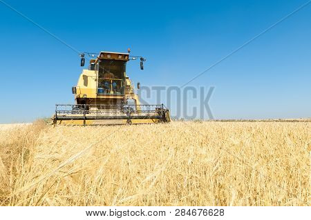 Agricultural Machinery Working On The Barley Tour With Sunny Day