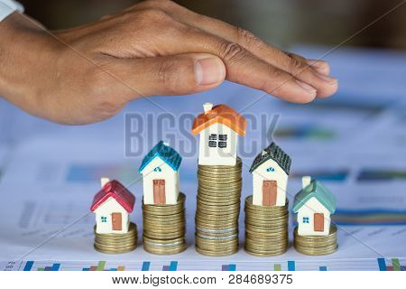 Hands As A Protecting Roof Over A Little House, Property Insurance And Security Concept. Protecting 