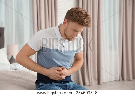 Young Man Having Nausea In Bedroom. Feeling  Sick