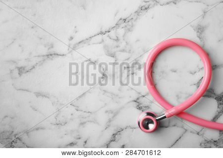 Pink Stethoscope Folded Like Awareness Ribbon On Marble Background, Top View With Space For Text. Br