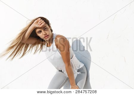 Active Tired Good-looking Caucasian Sporty Fitness Woman Wiping Sweat Forehead Gasping, Looking Asid