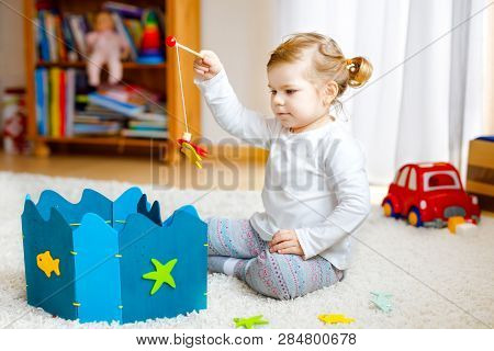 Adorable Cute Toddler Girl Playing With Wooden Fishing Game At Home Or Nursery. Happy Healthy Child 