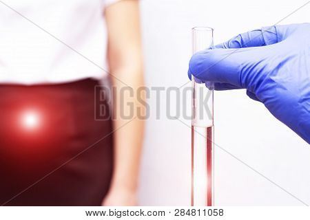 A Geneticist Doctor Holds A Test Tube With An Egg Against The Background Of A Girl Whose Patient Is 