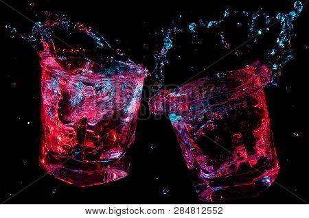 Rocks Glasses Toasting And Splashing Glowing Liquid Isolated On A Black Background