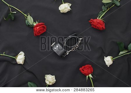 Obey Me...composition Of Red And White Roses With Black Leather Handcuffs Against Of Black Silk Fabr