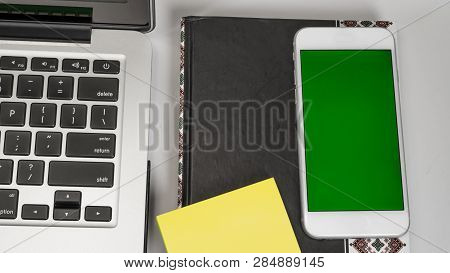 Office Workplace. Laptop, Notebook, Daily Planner, Glasses And Phone On White Background. Green Back