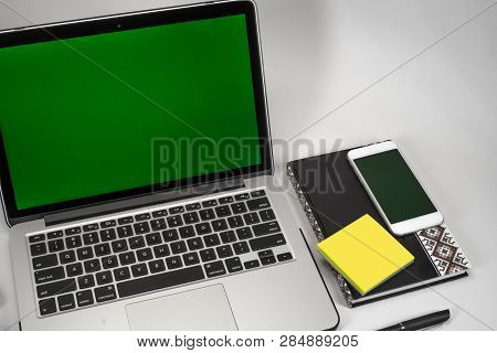 Office Workplace. Laptop, Notebook, Daily Planner, Glasses And Phone On White Background. Green Back