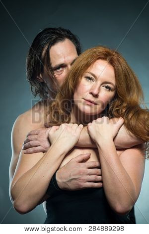 Adorable Bare Shouldered Woman Being Embraced By Her Shirtless Caring Husband While Gently Holding H